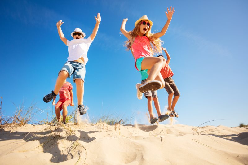 Kinder springen von der Düne in den Sand