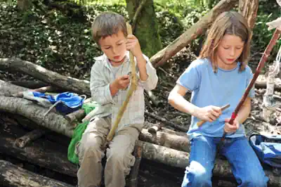 survivalcamp-sommer zwei-kinder-schnitzen-stoecker-fuer-das-lagerfeuer