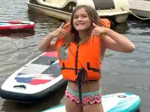 wassersport-ferien maedchen-mit-schwimmweste-freut-sich-aus-sup-wandern-beim-wassersport