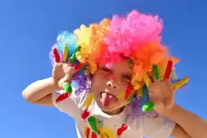 zirkus-sachsen ein-kind-mit-einer-lustigen-bunten-perruecke-macht-faxen