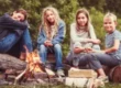 kinder-sitzen-auf-einem-baumstamm-am-lagerfeuer