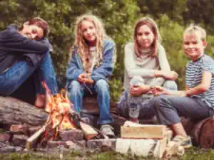 survival-camp-kinder kinder-sitzen-auf-einem-baumstamm-am-lagerfeuer