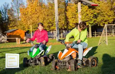 zwei-kinder-fahren-mit-dem-kleinquad-in-ihrer-freizeit-auf-dem-reiterhof