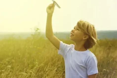 ein-junge-laesst-seinen-papierfliger-auf-einer-wiese-bei-berlin-steigen