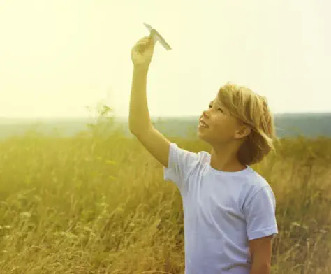 ein-junge-laesst-seinen-papierfliger-auf-einer-wiese-bei-berlin-steigen