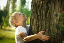 ostern-in-berlin ein Mädchen umarmt im Britzer Garten einen großen Baum.