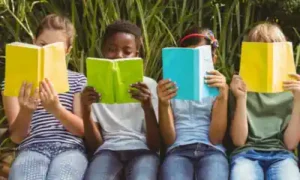 Vier Kinder sitzen nebeneinander und vertiefen ihre Englischkenntnisse im Ferienlager.