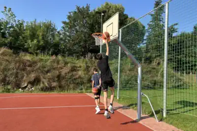 ein Junge netzt gerade den Basketball in Basketballkorb ein