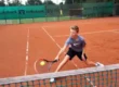 ein Junge setzt einen Lop im Tennis Feriencamp an