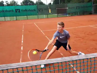 ein Junge setzt einen Lop im Tennis Feriencamp an