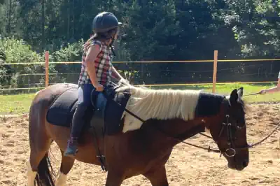 ein Kind reitet auf einem Pony an der Longe