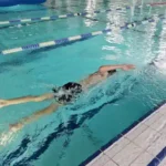 sportcamp-schwimmen ein Reiseteilnehmer zieht seine Bahnen in der Schwimmhalle im Sportcamp