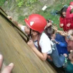 ferienlager-waldfrieden alle Kinder überwinden gemeinsam einen Parkur mit einer Kletterwand