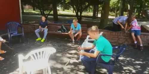 ein Gruppe von Kindern schnitzen sich etwas kreatives aus Holz