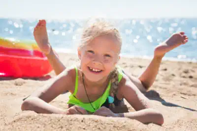 ein Mädchen strahlt vor Freude am Strand an der Ostsee