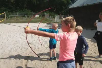 die Kinder lernen im Bogenschießen im Ferienlager