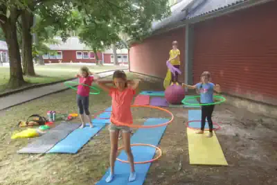 vier Mädchen üben für das Zirkuscamp mit Laufkugel und Hula Hoop