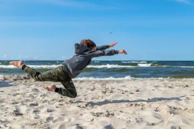 ein Junge springt am Strand voller Freude und Elan in den Sand