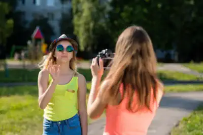 zwei Mädchen probieren mit einem Camcorder Posen aus