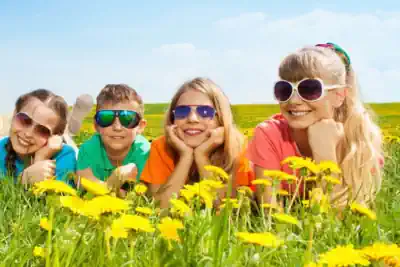 3 Mädchen und ein Junge liegen auf einer Wiese und filmen den Sommer